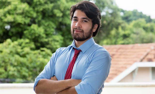 serious looking hispanic man in tie with arms crossed